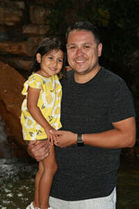 A dad holds his daughter as they smile for a picture